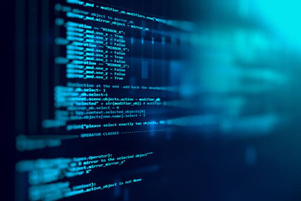 Close-up of a screen displaying lines of blue and white computer code on a dark background.