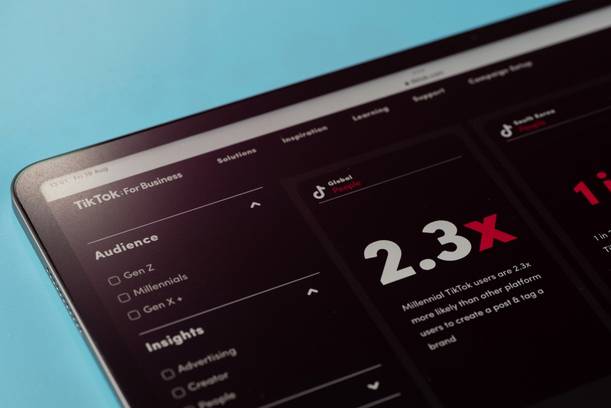 Smartphone screen displaying TikTok business insights with audience data and a large "2.3x" growth metric in white and red on a black background.
